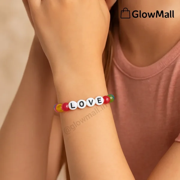 A person's wrist wearing a colorful beaded Glow Mall bracelet with white circular beads spelling out the word 'LOVE'.