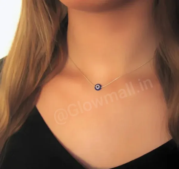 A woman wearing a sleek, minimalist silver-plated evil eye necklace from Glow Mall, paired with a black top.